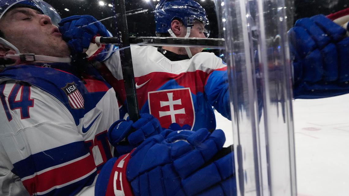 Slovakia's Juraj Slafkovsky (20) challenges with United States' Brock Faber (14) during a men's ice hockey semifinal game