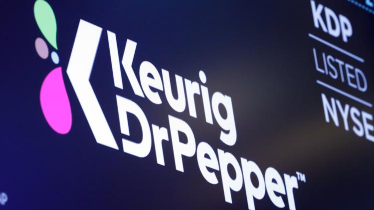 The logo for Keurig Dr. Pepper appears above a trading post on the floor of the New York Stock Exchange, July 12, 2018. (AP Photo/Richard Drew, File)