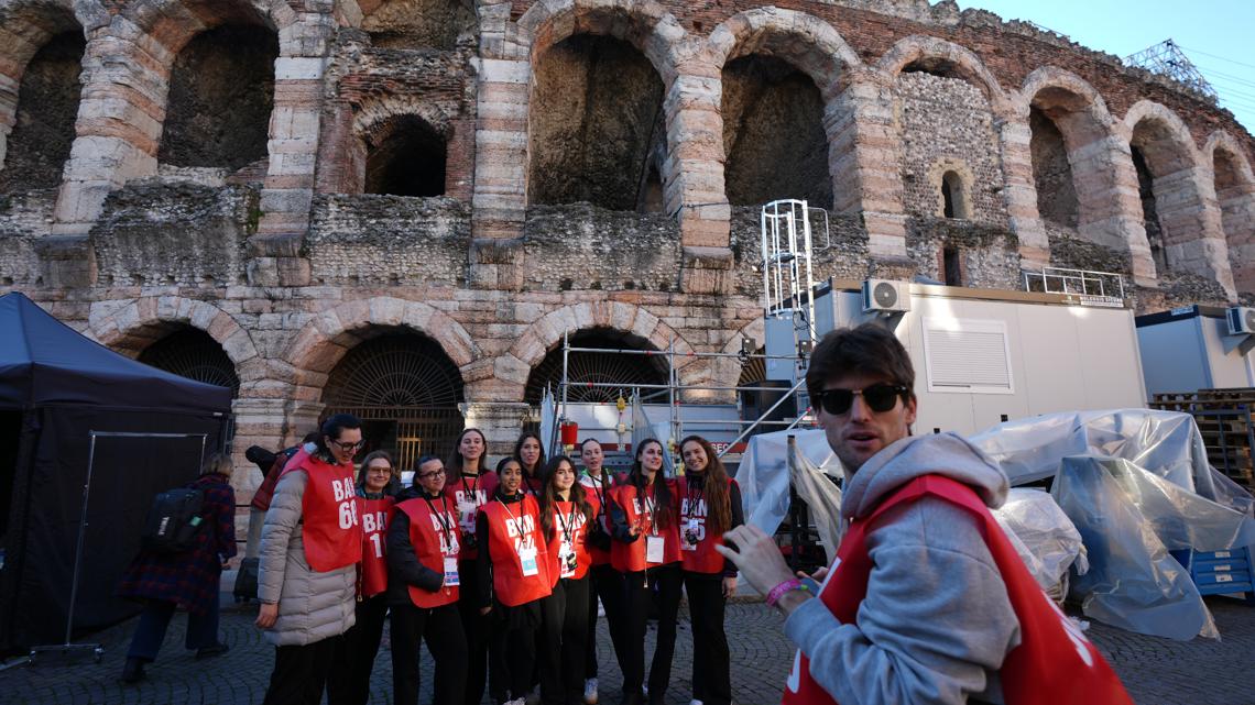 Volunteers stand close to the Arena ahead of the closing ceremony at the 2026 Winter Olympics, in Verona, Italy, Tuesday, Feb. 17, 2026.