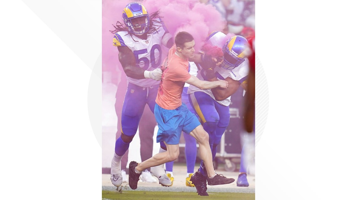 Pictures: Linebacker flattens protester who ran on field with pink smoke  device