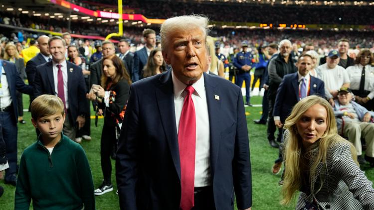 President Donald Trump, center, with his grandson Theodore, left walks on the field before the start of the NFL Super Bowl 59.