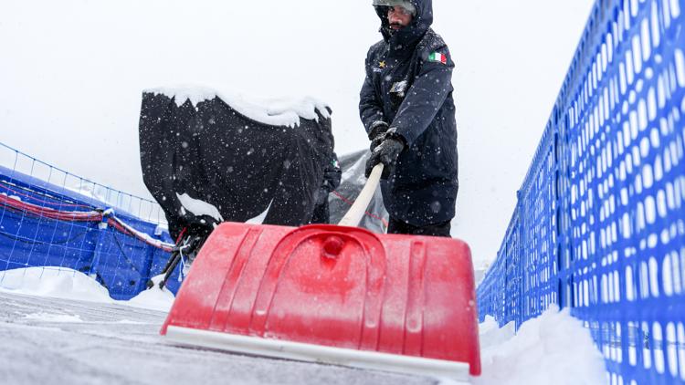 A man shovels at Livigno Snow Park after the men's freestyle skiing halfpipe qualifications were delayed on Feb. 19, 2026, in Livigno, Italy.