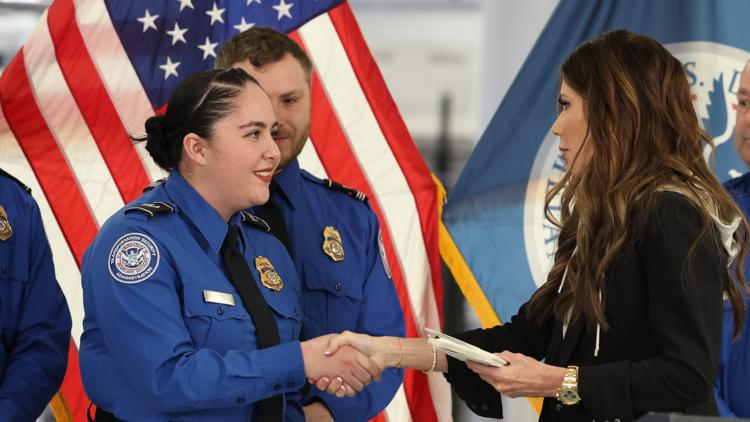 U.S. Homeland Security Secretary Kristi Noem, right, shakes hands with Transportation Security Administration Officer Monica Degro.