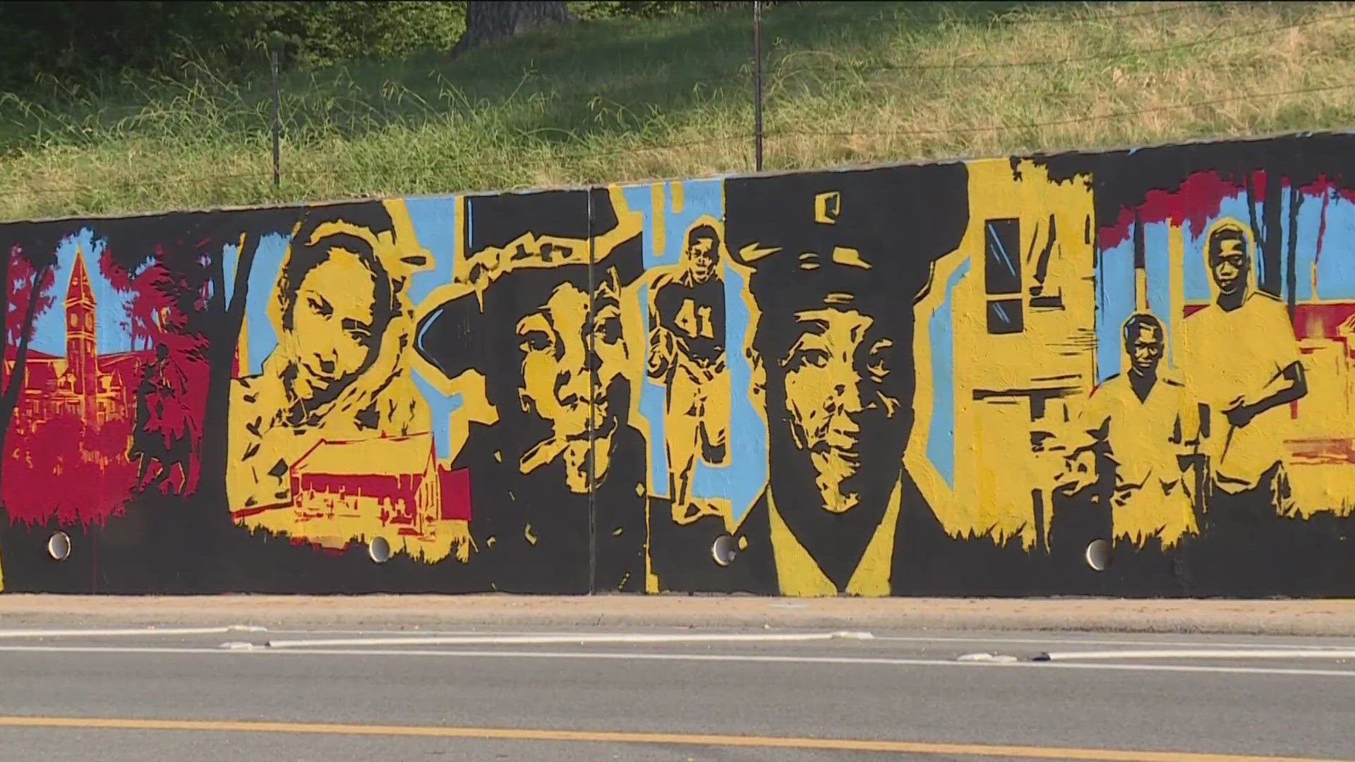 The mural is 90 feet long. It is part of an ongoing effort to cover a 500-foot-long concrete retaining wall along the road with murals by 2028.