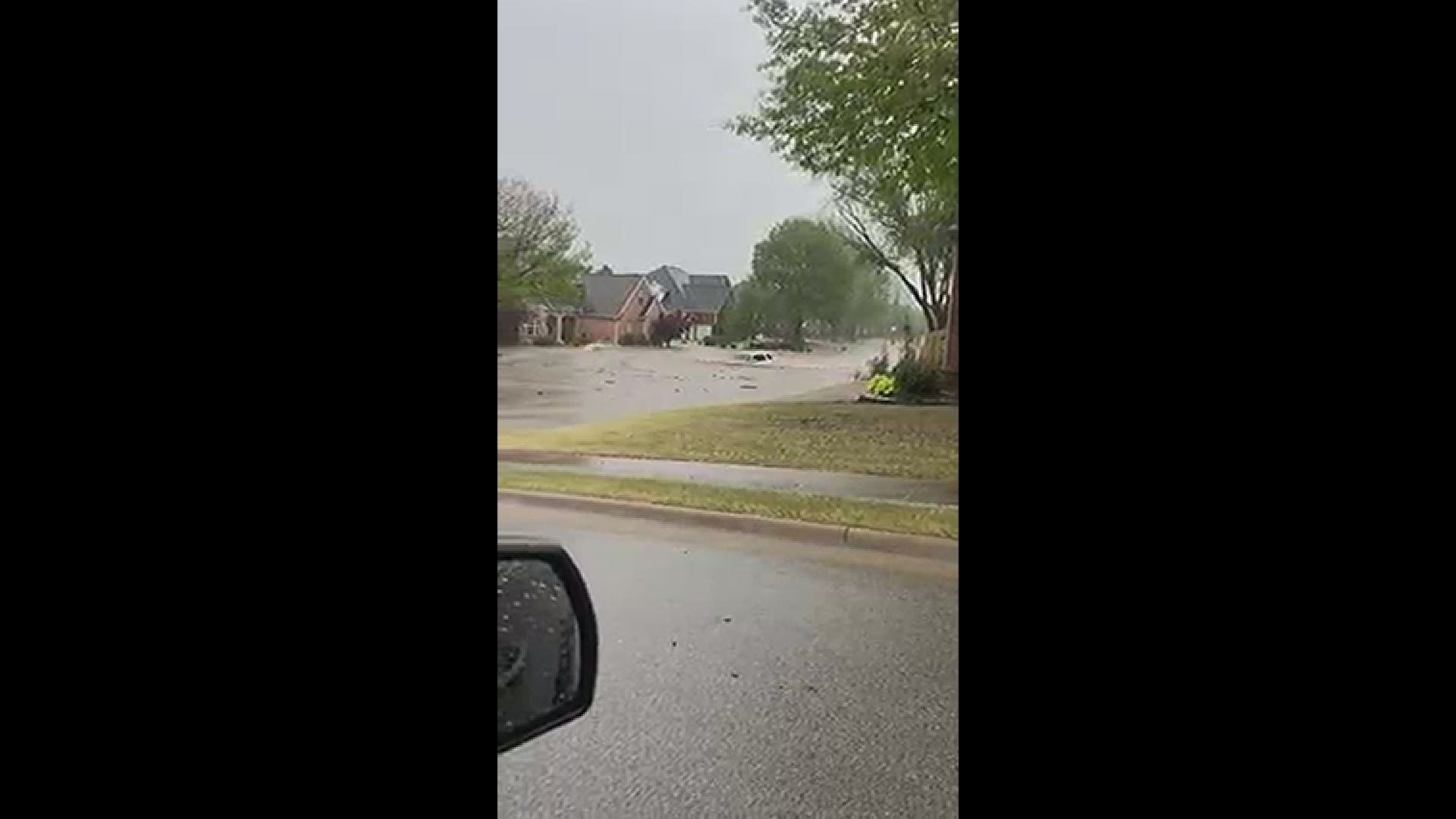 Video shows a car dangerously drive through a flooded Rogers neighborhood.