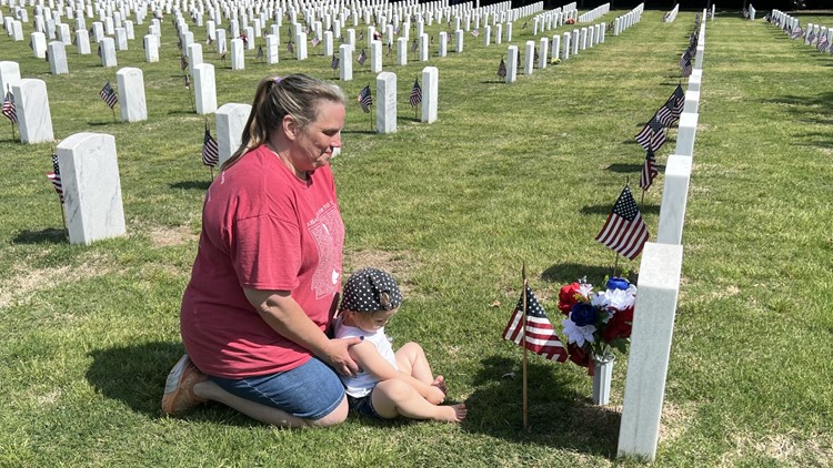 Community and family members place flags on headstones at Fayetteville National Cemetery