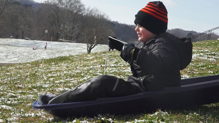 Kids sled through the snow day, dodging grass and leaves Kids sled through the snow day, dodging grass and leaves