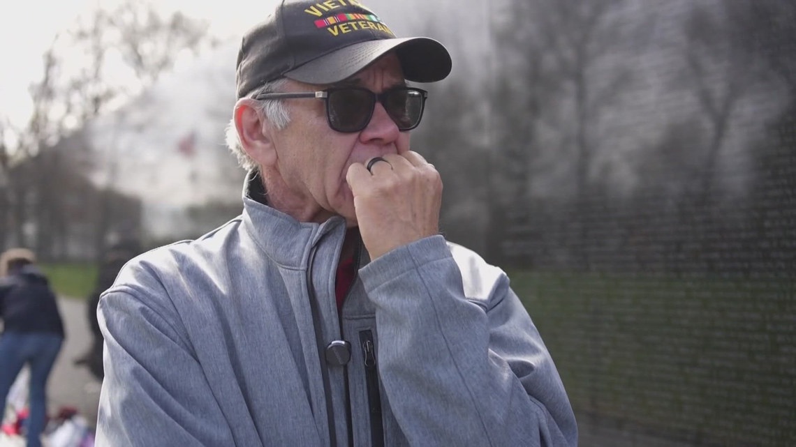 The polished black granite of the Vietnam Veterans Memorial reflects more than the faces standing beside it— it ref...