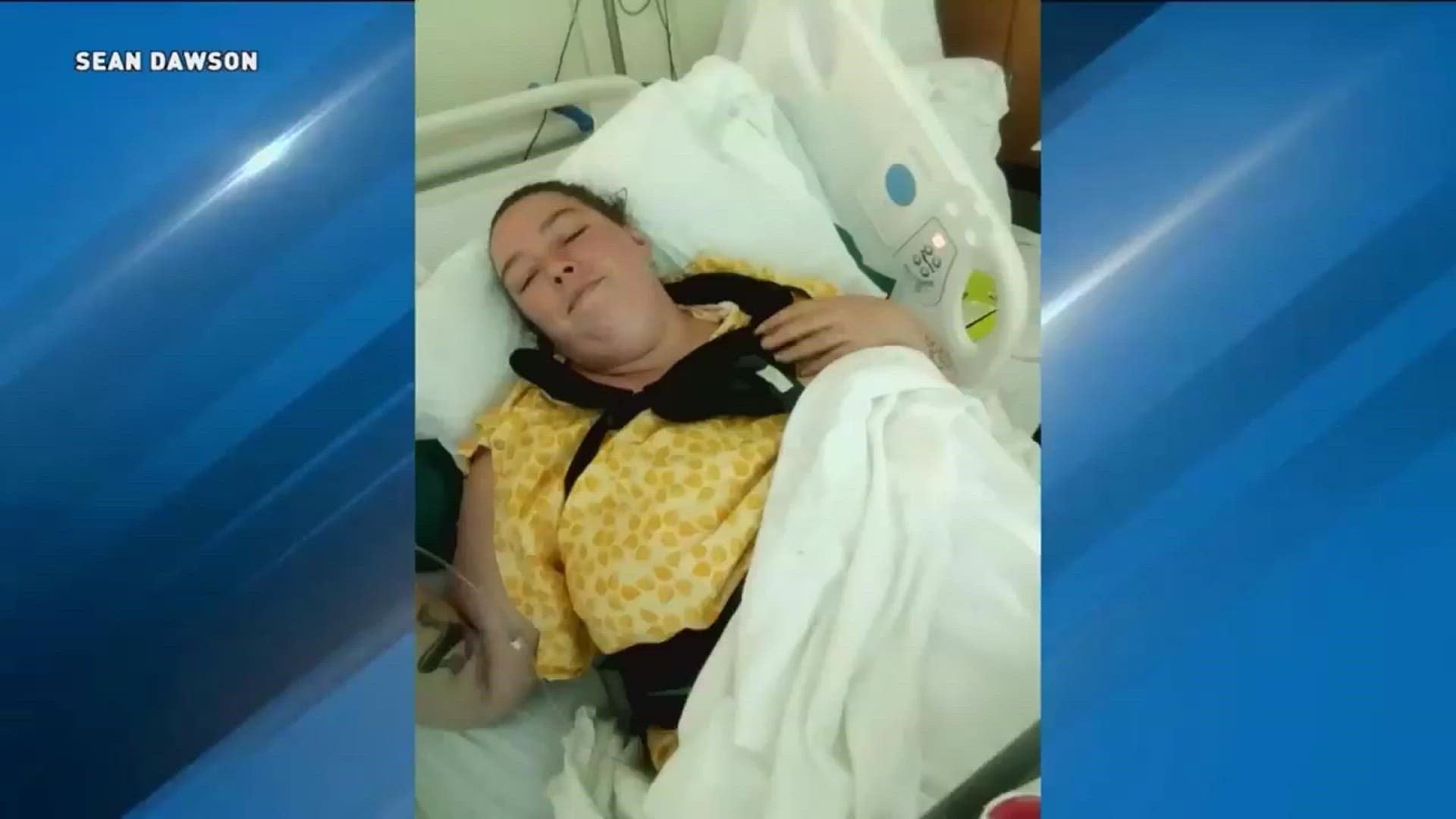 The mother is hospitalized and unable to walk after a vertebrae in her spine shattered.
