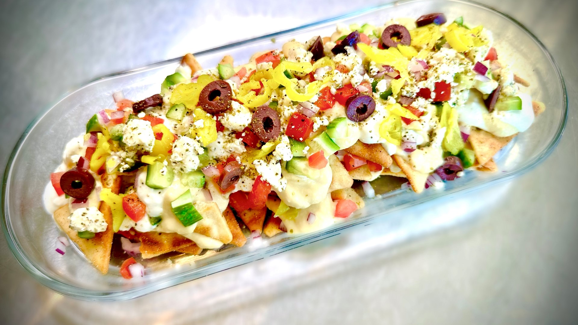 These greek nachos make a great party snack! Throw some pita chips, olives, cheese, veggies and hummus together for this tasty dish.