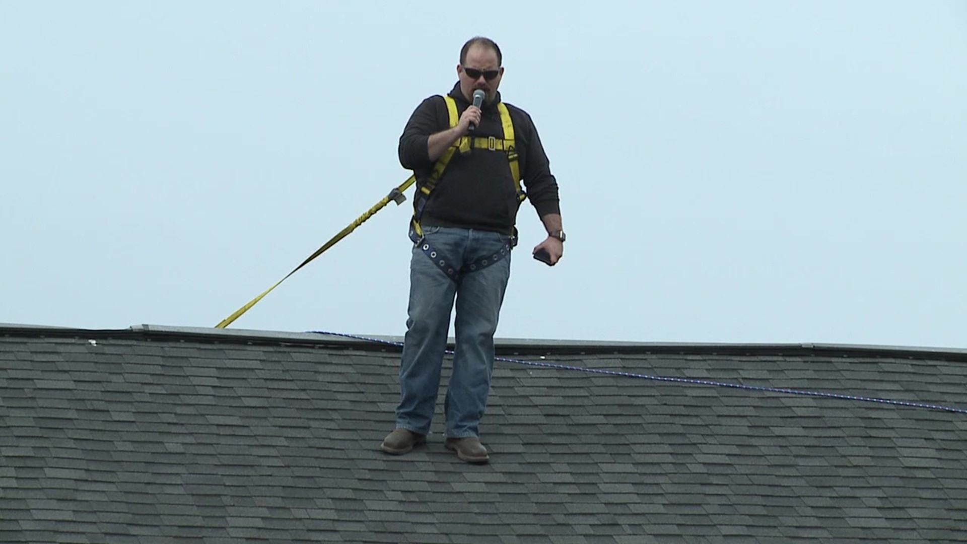 Outfitted with a safety harness, Pastor Heuer stood atop his church building, preaching into a radio transmitter.
