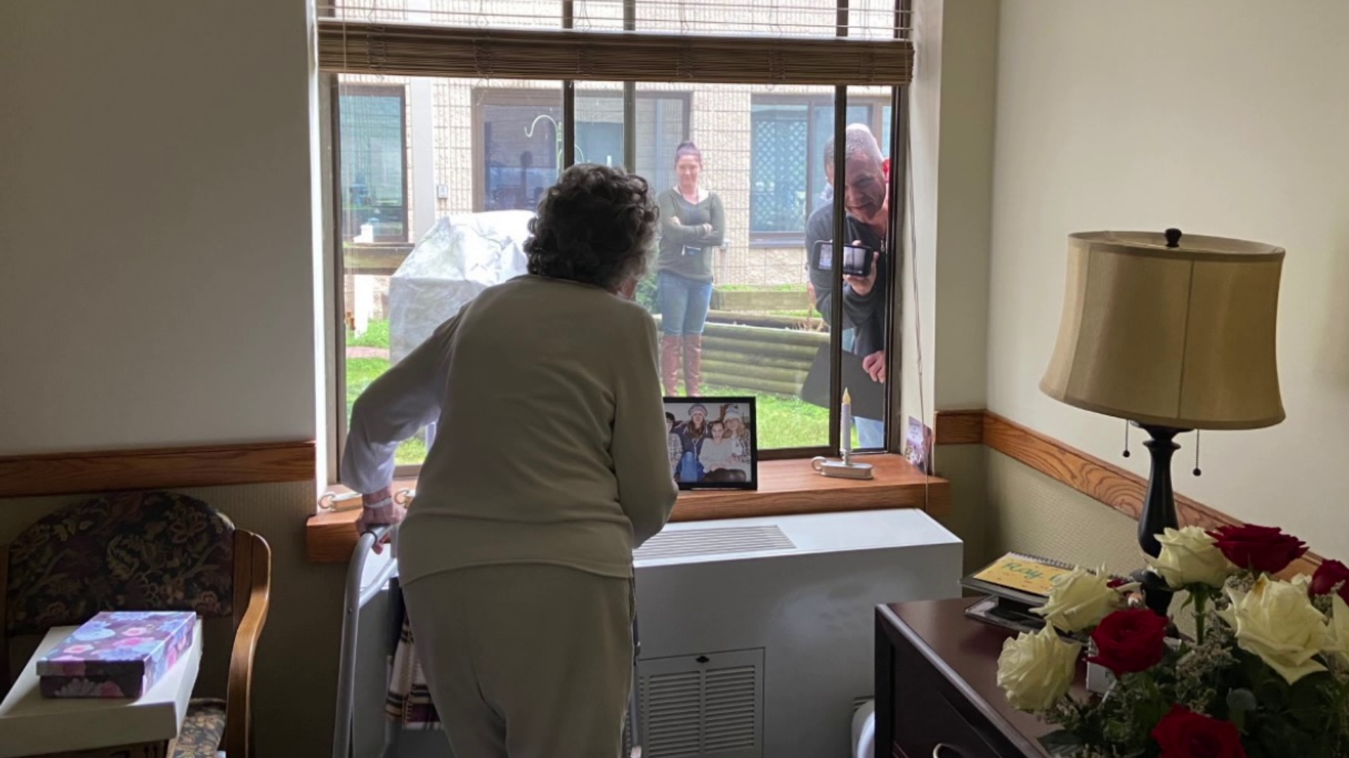 Woman in senior living facility is honored through the glass.