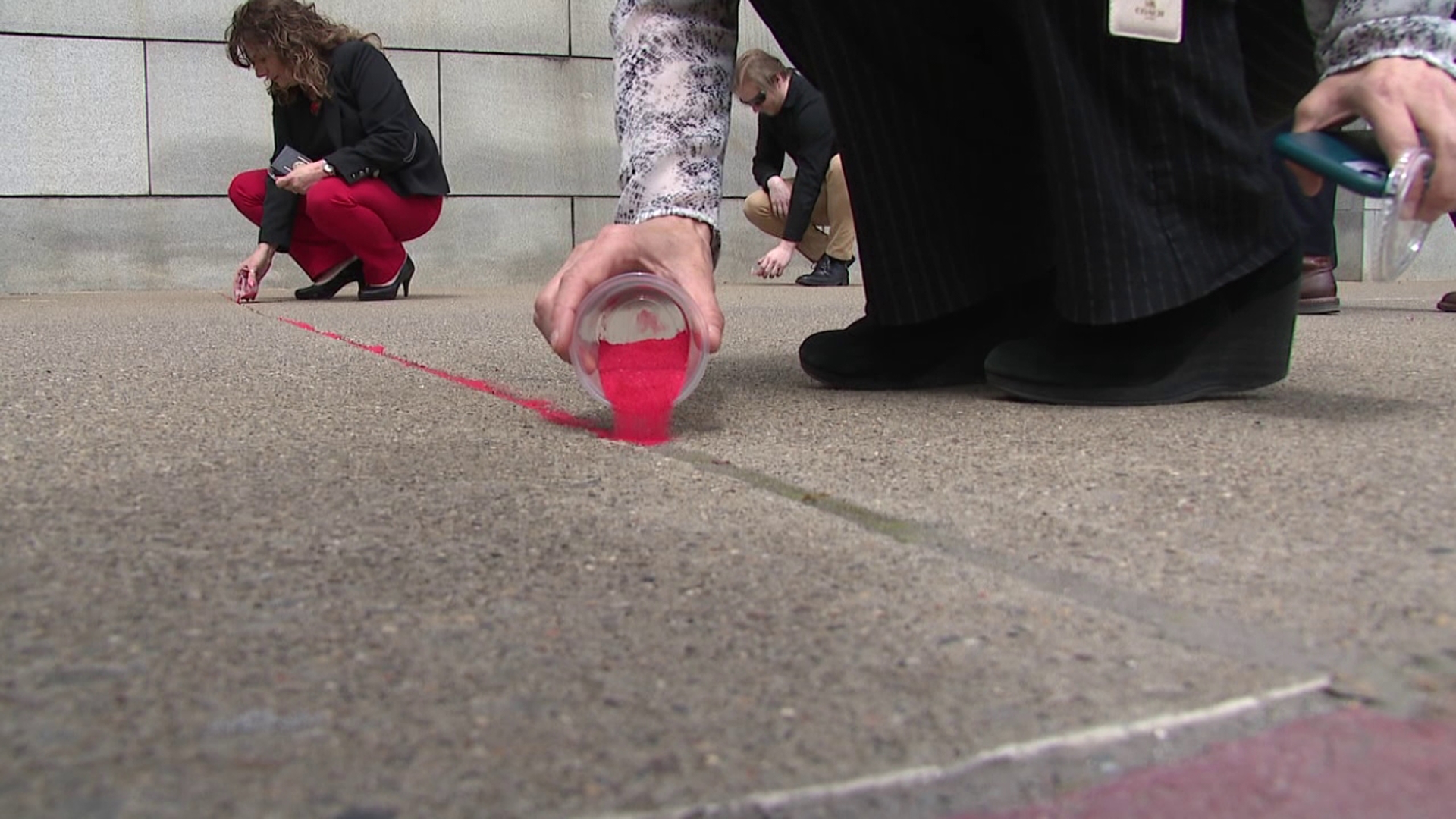 Grains of red sand fill pavement cracks at Scranton's Federal Courthouse, representing millions of victims exploited by human trafficking.