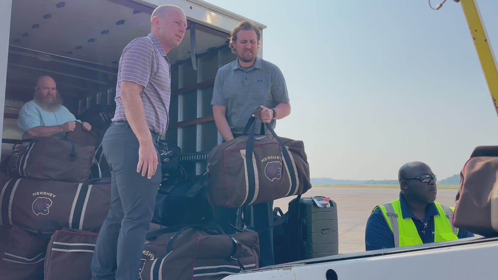 The team's equipment personnel take gear off the truck and onto the plane.