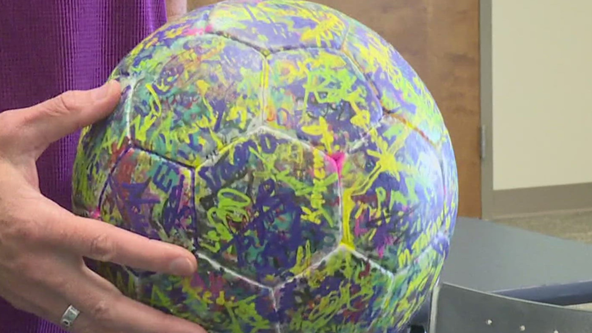 Dr. Karli Richards collects signatures on a special ball to spread message about positive climate action and gender equality for women in sports .