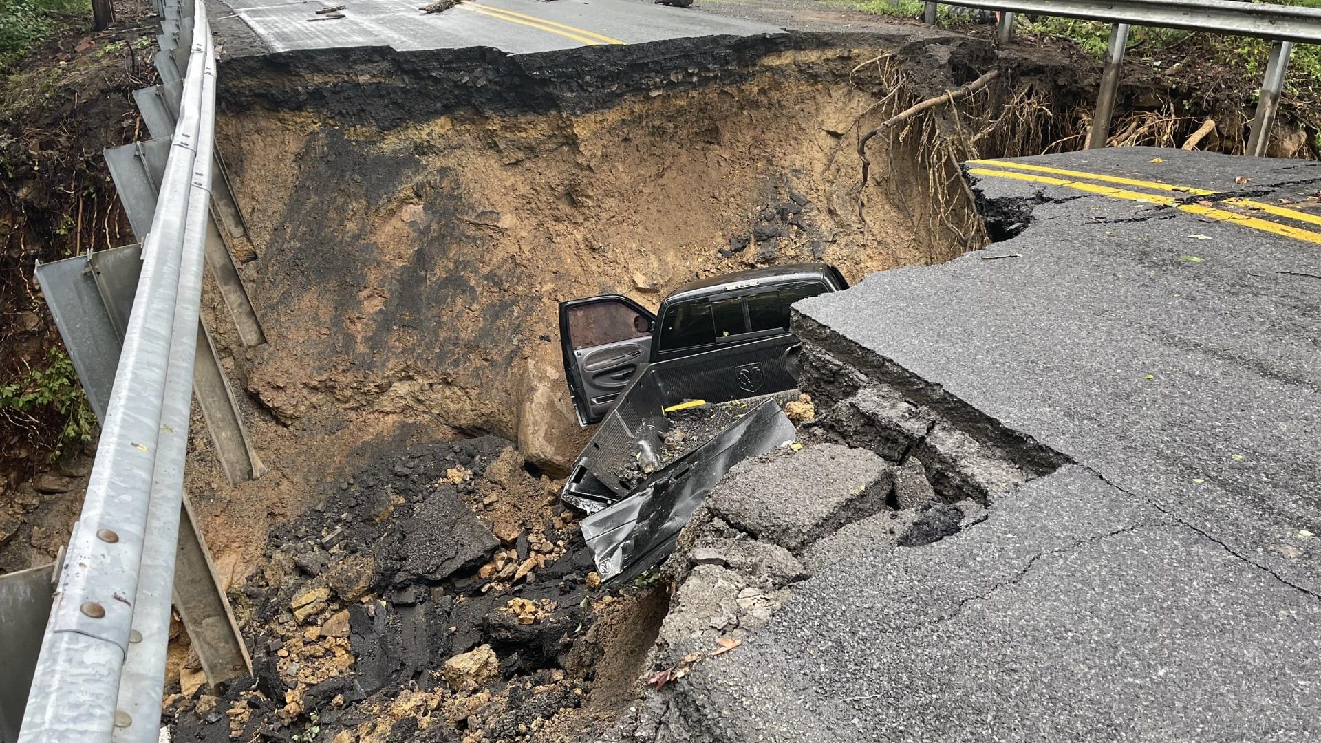 The vehicle is banged up, with the driver's door ajar and back tailgate seemingly askew. The driver climbed out of the sinkhole with minor injuries.