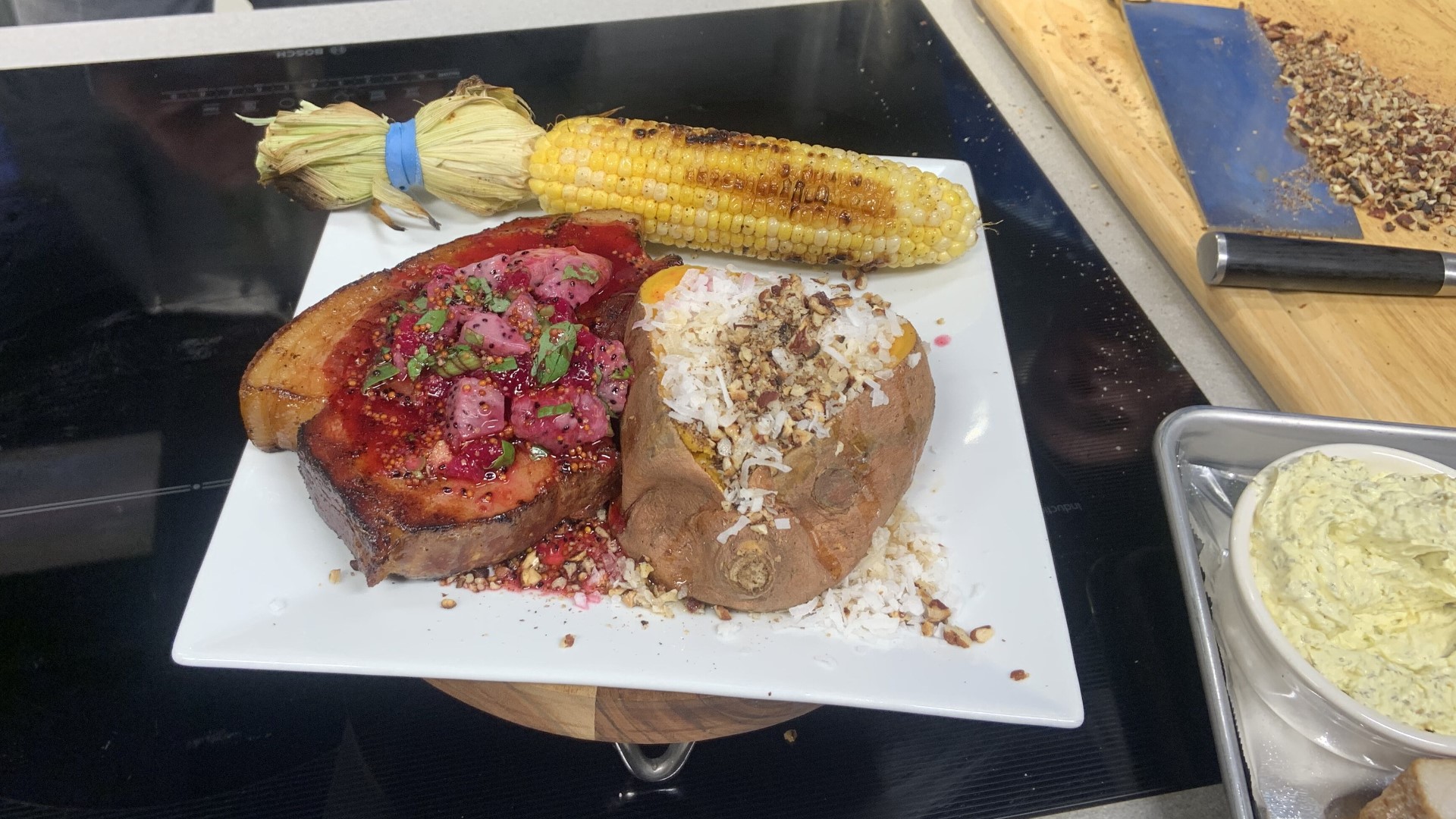 Olivia's prepared a thick cut smoked pork chop topped with a dragon fruit drizzle, served alongside corn on the cob and a sweet potato.