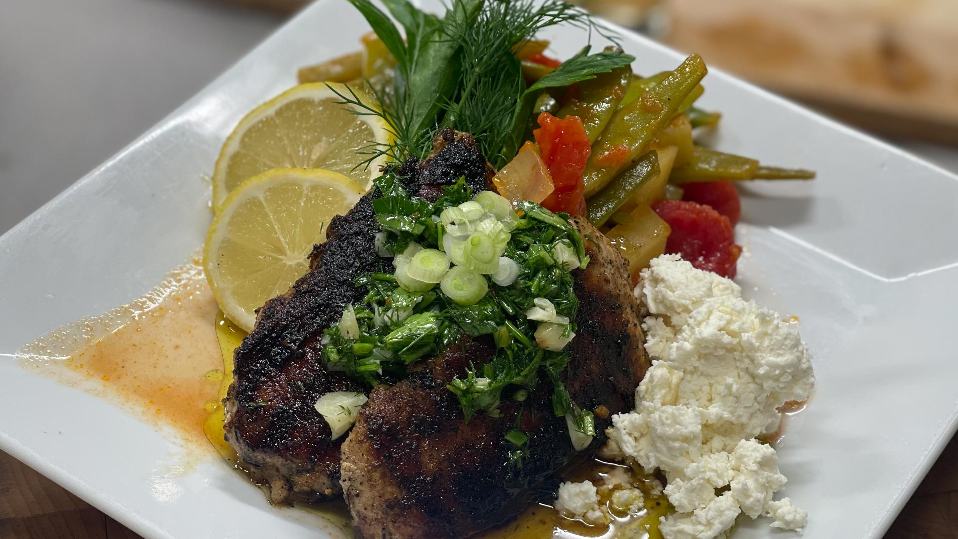 Fire-grilled pork chops are topped with a Greek Style Chimichurri and served with Greek style beans and potatoes.