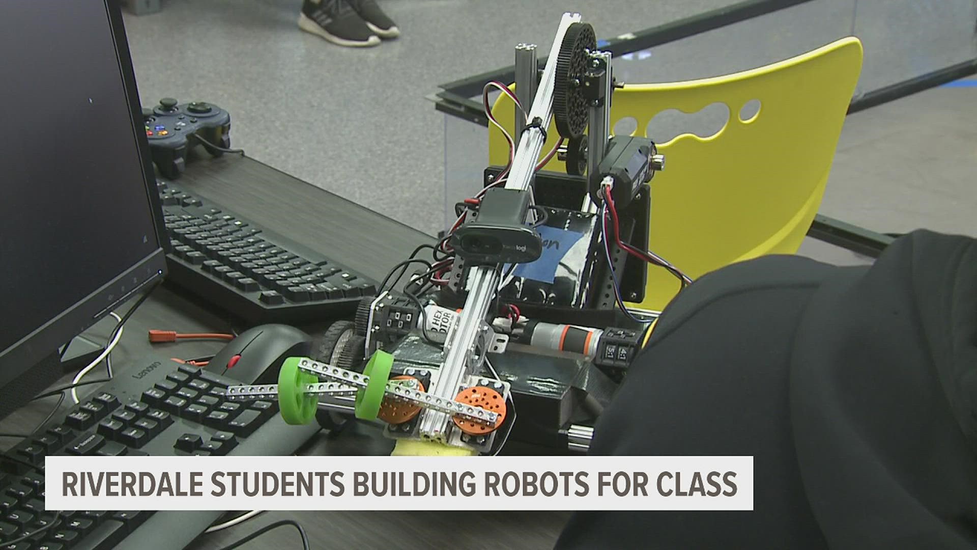 Riverdale High School students show off their robots that they created in their classroom.