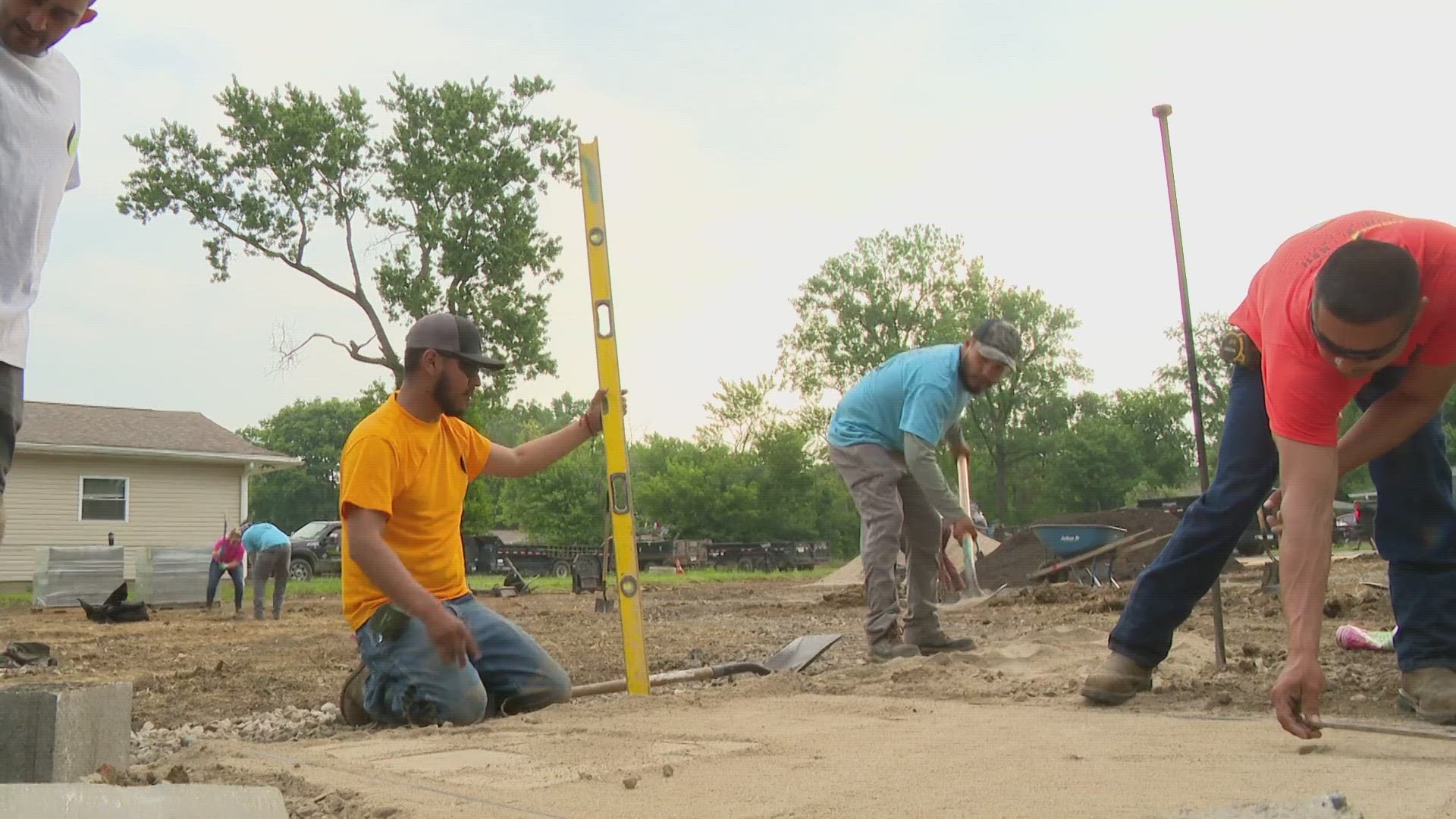 Workers put down gravel for a walking path, trees, and mulch and soil for multiple garden beds for the community to enjoy.