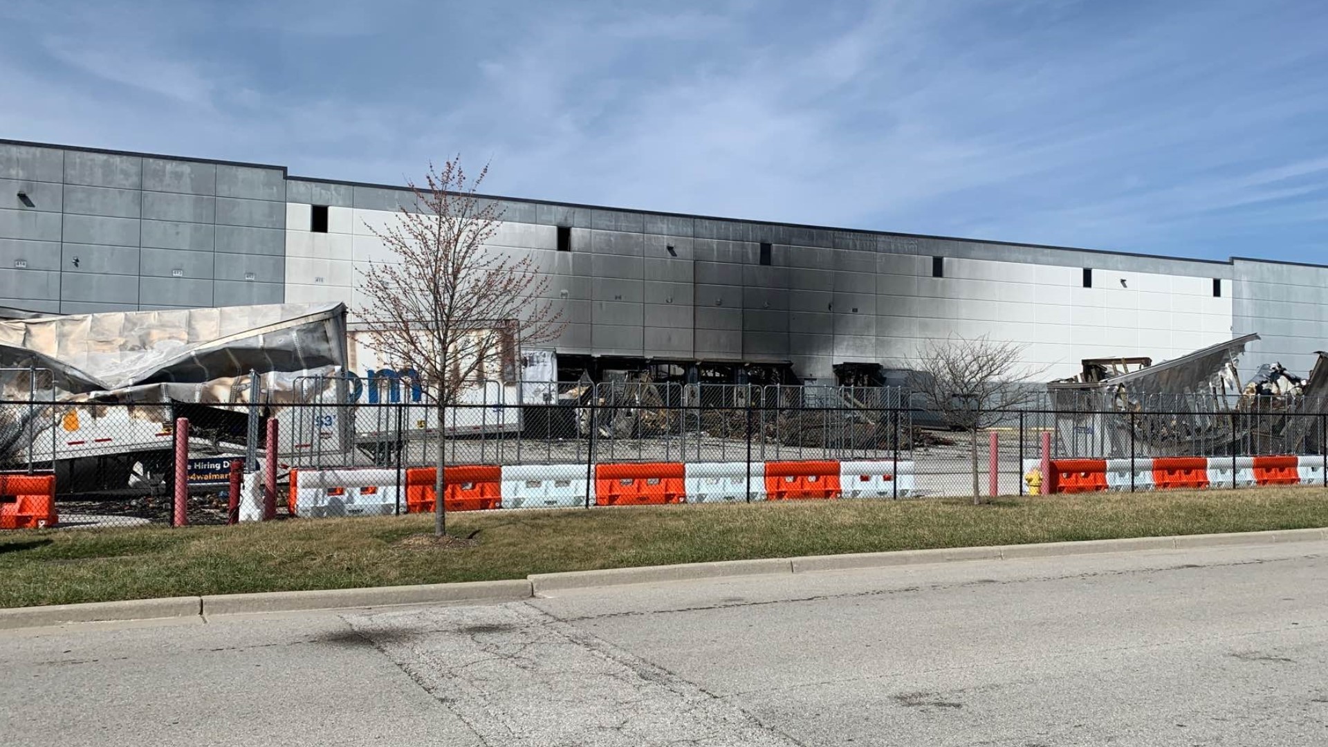 A trailer was still smoldering in the parking lot and the smell of fire lingers around the Plainfield fulfillment center that caught fire last week.