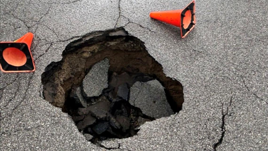 'It just keeps getting bigger' | Neighbor says she's been directing traffic to help motorists avoid huge sinkhole on...