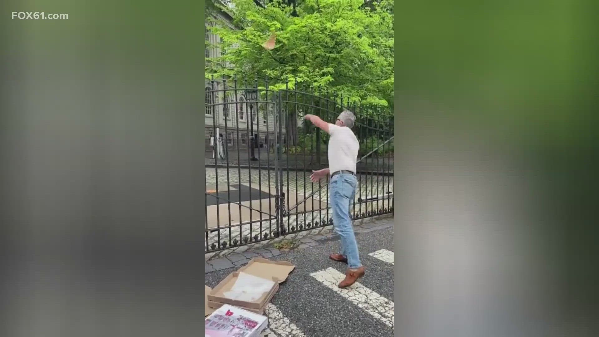 The man shouted "Give us pizza or give us death," as he threw slices over the gate.